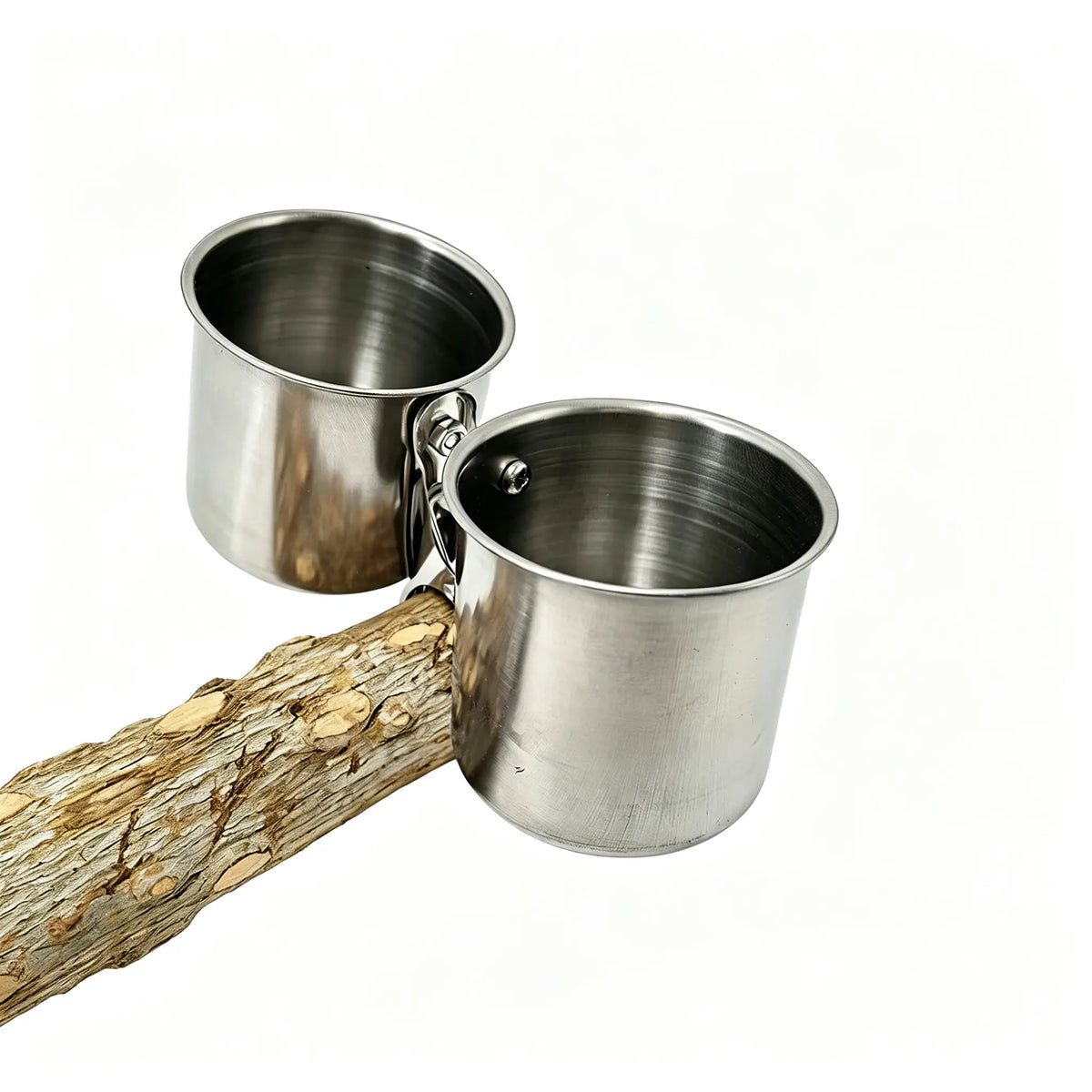 Two stainless steel feeding cups with attached metal clips, shown resting on a textured log against a plain white background.